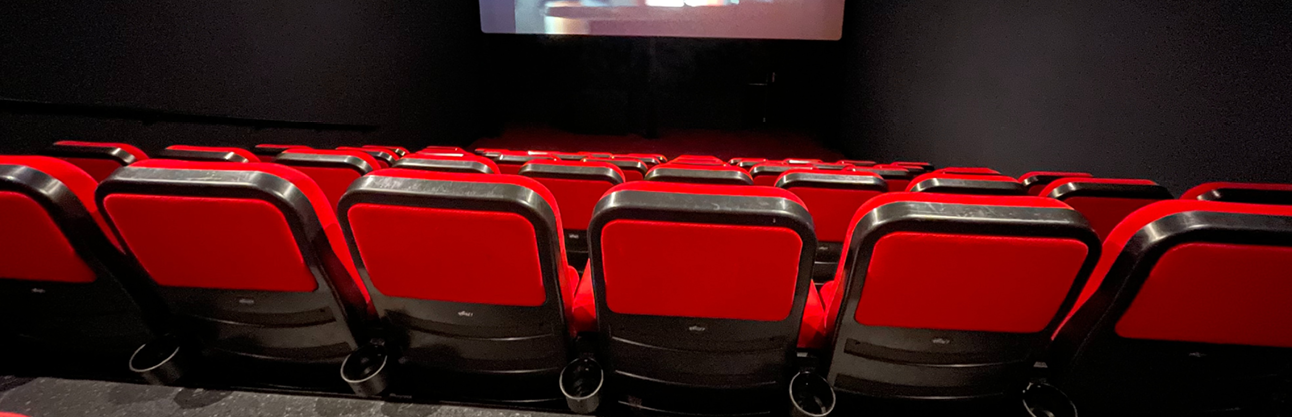 A row of cinema chairs in front of a theatre.